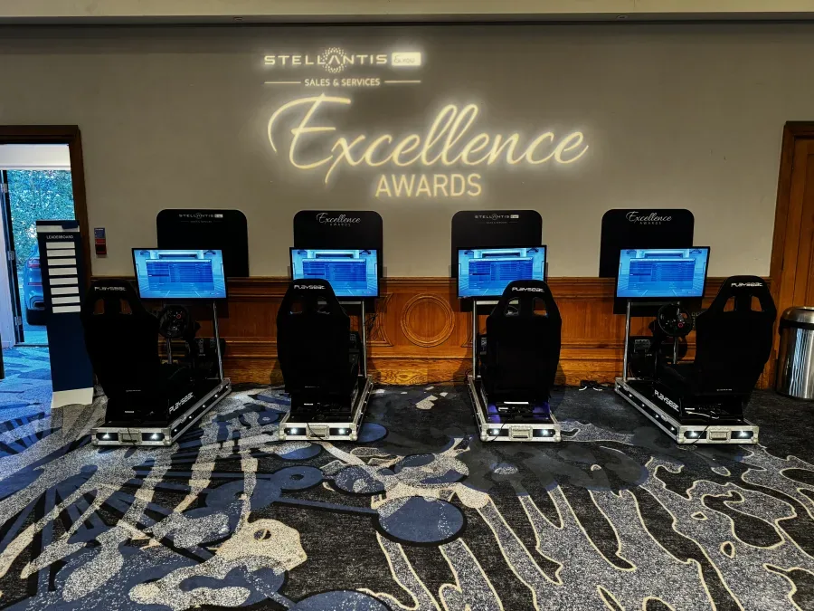 Four branded racing simulators with a digital leaderboard totem at an awards evening
