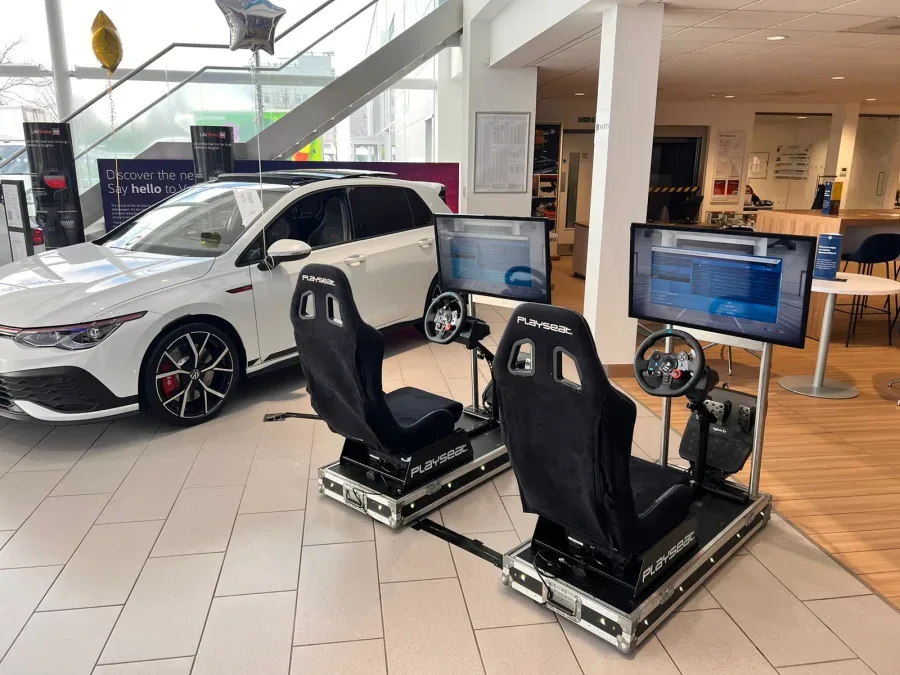 Driving simulators in a car showroom next to a hot hatch