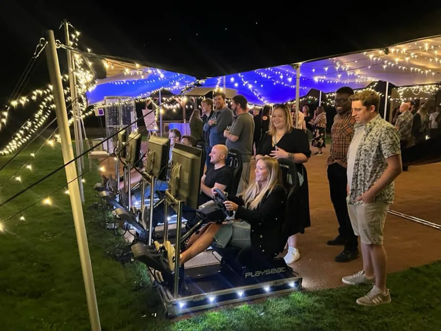 Guests racing on simulators in an outdoor marquee at night