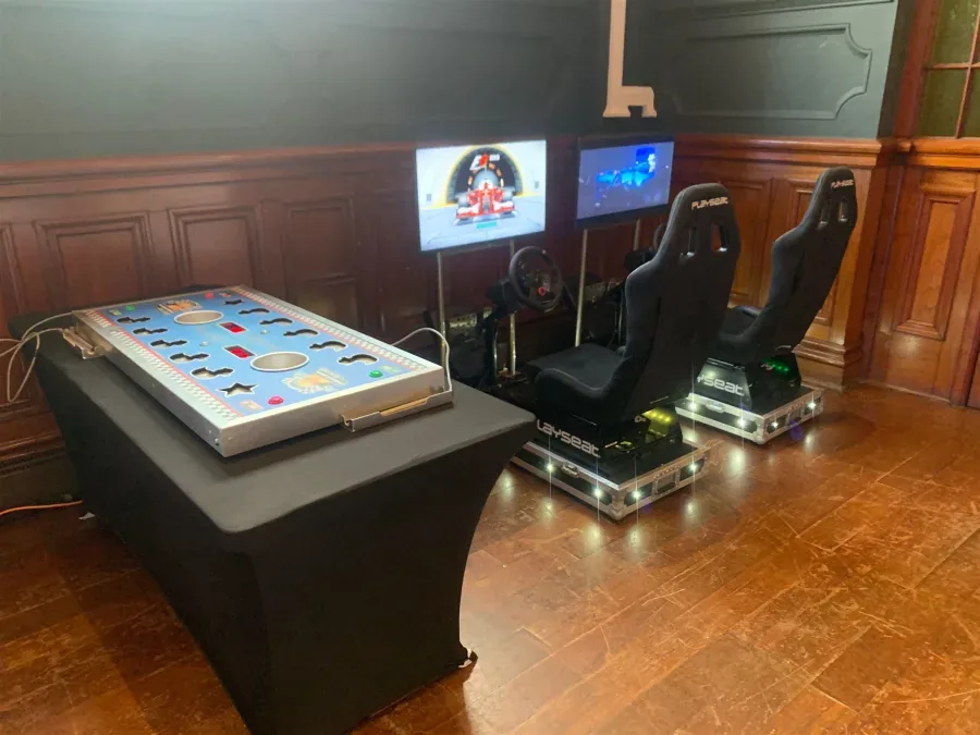 Racing simulators set up next to another event game at a party